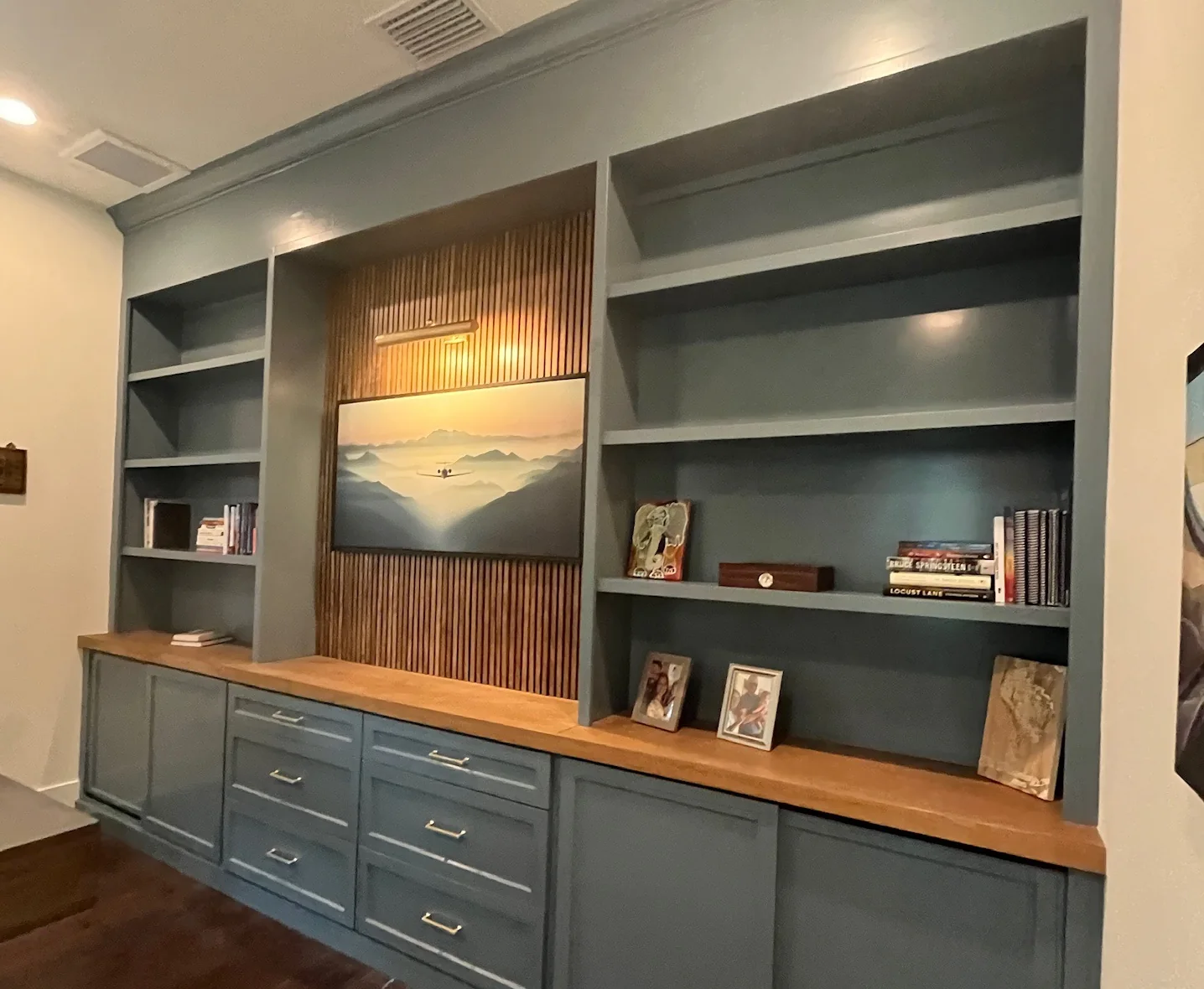 Slate-blue custom built-in with a wood slat panel and a wood countertop by Frost Custom Carpentry in Tampa, FL